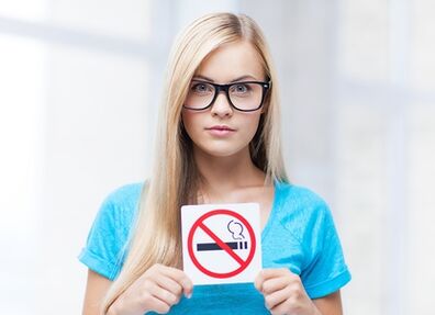dekle, ki ima pred vhodom tablo za prepoved kajenja